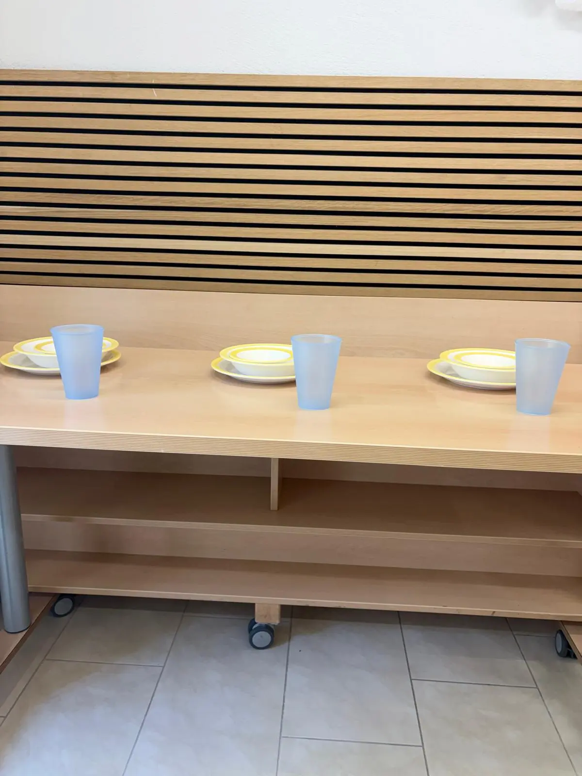 Gedeckter Essplatz der Vorkindergarten-Gruppe mit gelben Tellern und blauen Bechern