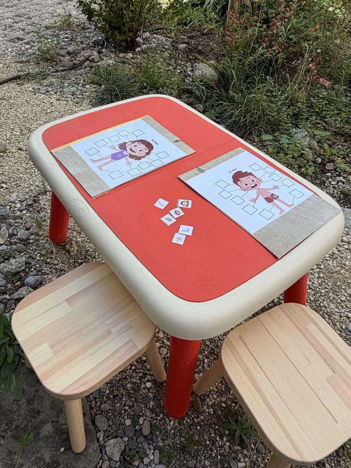 Kindertisch im Garten mit Lernblättern zum Körper und kleinen Bildkarten